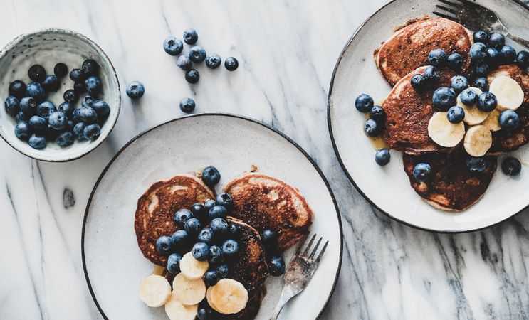 Pancakes with banana, blueberries on marble table