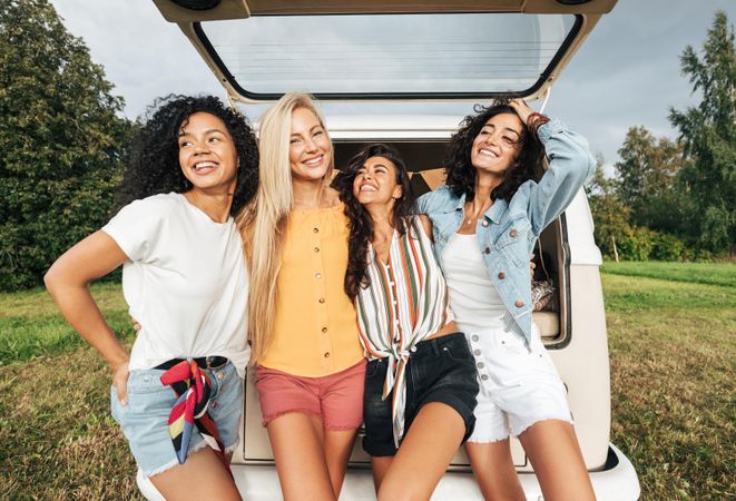 Happy women posing by the trunk of a van