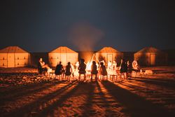People gathering around burning fire in desert
