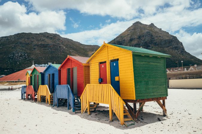 Blue yellow and green wooden house on light sand