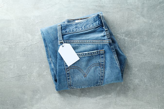 Folded jeans with a tag on a light background
