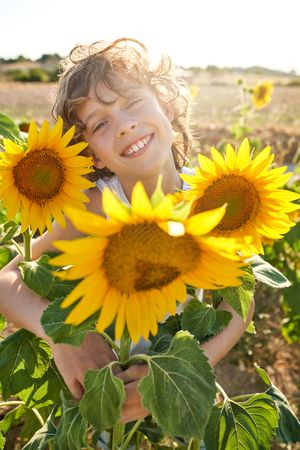Cheerful boy surrounded by sunflower in field