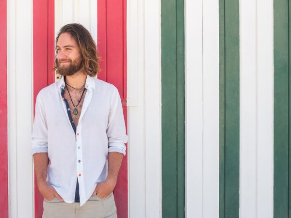 Cheerful guy standing near striped wall