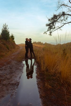 Men hugging and kissing near water puddle