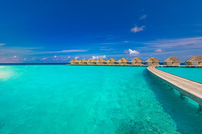 Walkway over clear blue water leading to vacation huts in the Indian Ocean