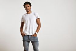 Man with neutral expression in plain t-shirt and jeans with hands in pocket in studio shoot