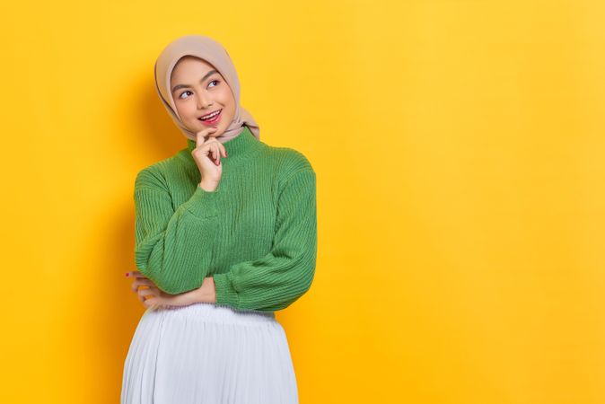 Woman in headscarf thinking and looking at yellow copy space
