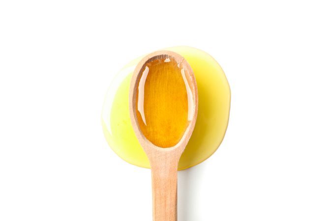 Wooden spoon with honey isolated on blank background, top view