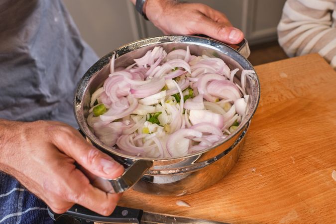 Unrecognizable person with pot of chopped onion