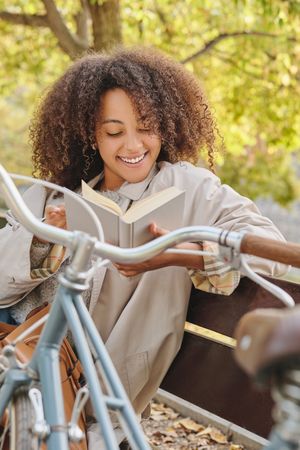 Smiling Black Latina  woman reading book in park