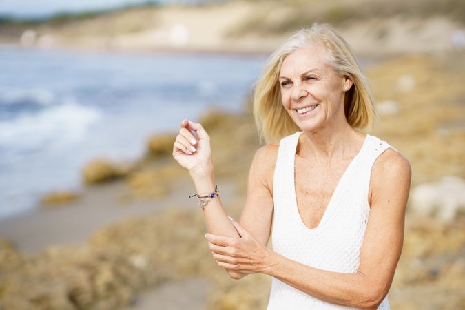 Older woman smiling on a rocky beach