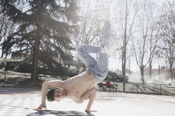 Shirtless man dancing break dance in park