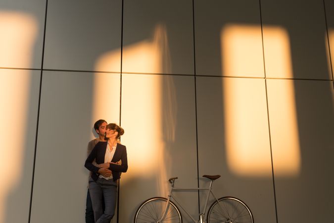 Happy colleagues hugging near bicycle