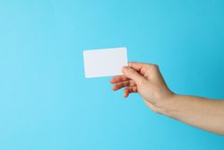 Female hand holding empty business card on blue background