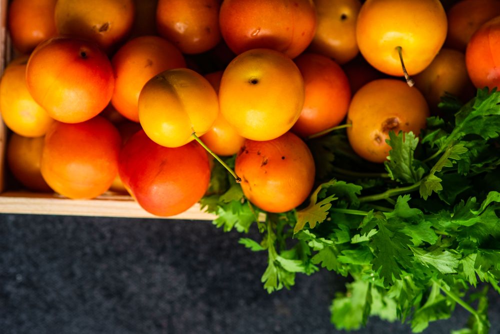 Top view of wooden box of plums with parsley