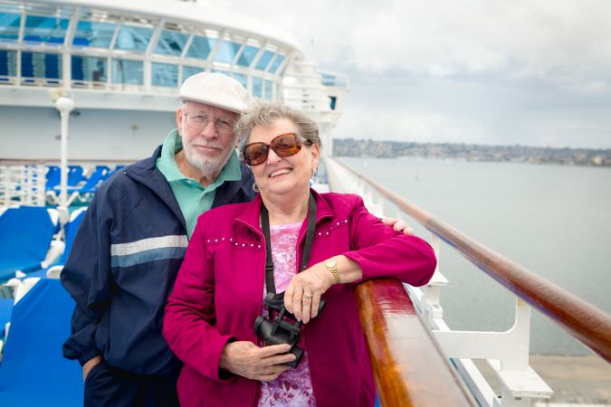 Smiling Adult Couple Enjoying The View From Their Passenger Cruise Ship with Their Bonoculars.
