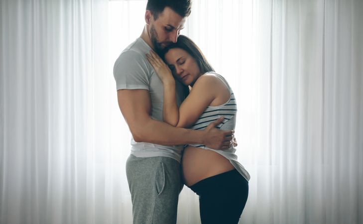 Pregnant woman embraced by her husband