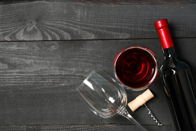 Flat lay composition with bottle of wine, glasses and corkscrew on wooden background, copy space