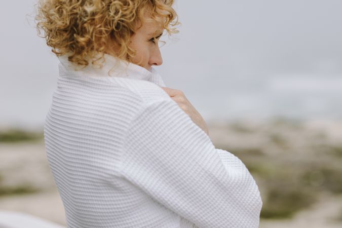 Close up of a woman in white coat looking at the sea