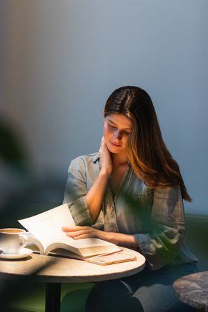 Calm woman reading book at cafe table