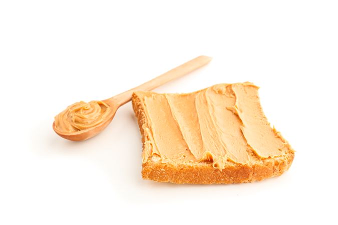 Peanut butter sandwich and wooden spoon isolated on light background. A traditional product of American cuisine