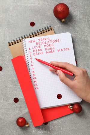 Envelope, notepads and hand with pen on gray background, top view