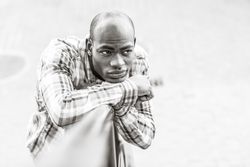 Monochrome picture of male in plaid shirt leaning on railing with listless expression