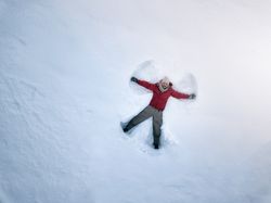 Smiling man lying on fresh clean snow
