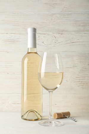 Corkscrew, bottle and glass with wine on blank wooden background, copy space
