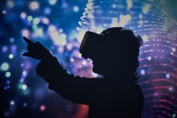 Silhouette of anonymous kid touching air while exploring virtual