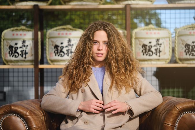 Stylish woman sitting in leather armchair on terrace