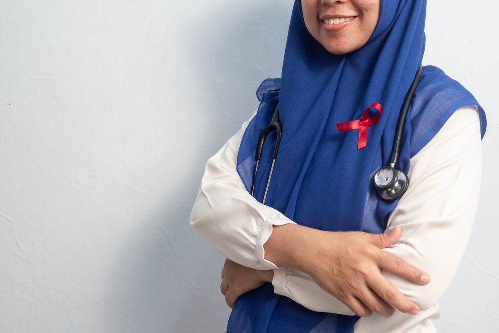 Close up Muslim Female Asian doctor or nurse wearing Red ribbons on cloth, HIV awareness concept, world AIDS day, world cancer day.