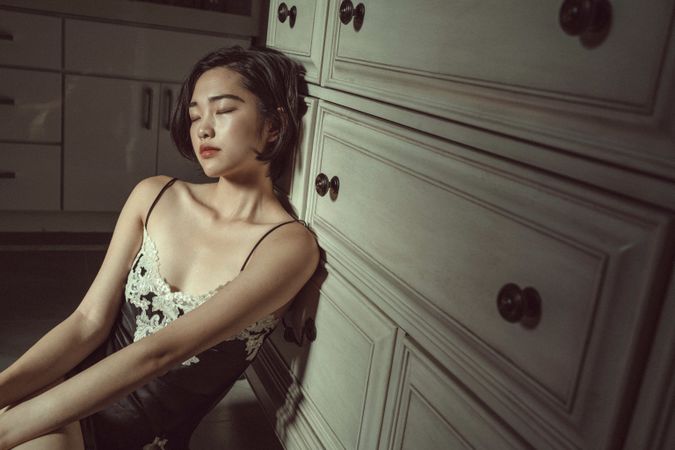 Woman in lingerie sitting on floor closing her eyes