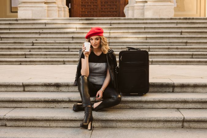 Cheerful tourist drinking on steps