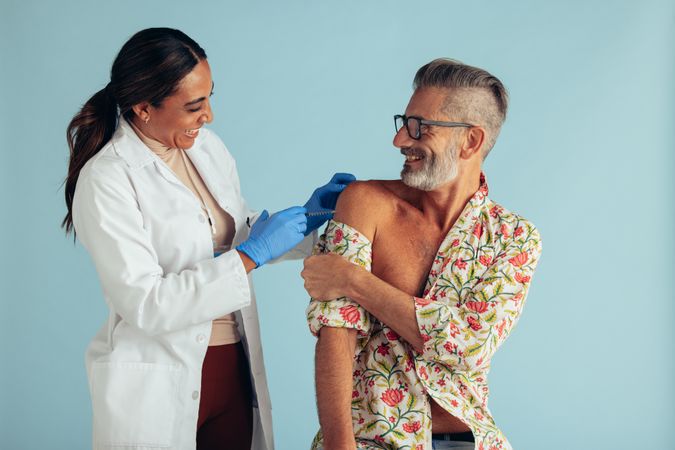 Smiling man getting flu shot from a female doctor