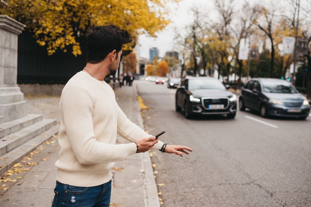 Young male hitchhiking with smartphone