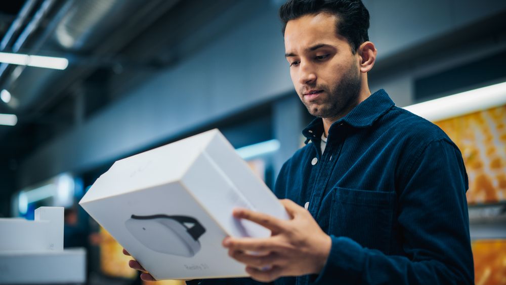 Portrait of a Stylish Man Looking at a Box with Modern VR Headset, Reading Model's Specifications and Features.