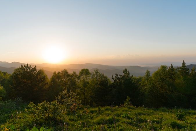 Sunset over forested hills with sky.