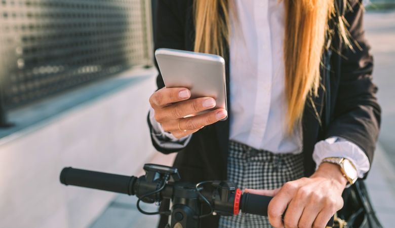 Detail of mobile of businesswoman with electric scooter