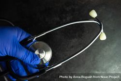 Top view of hands wearing purple latex gloves holding a medical stethoscope bxAPqM