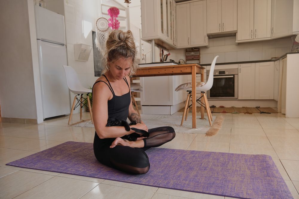 Woman with cat meditating in lotus pose in kitchen