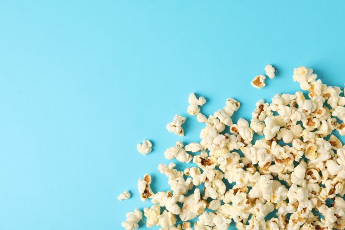Flat lay composition with popcorn on blue background, copy space