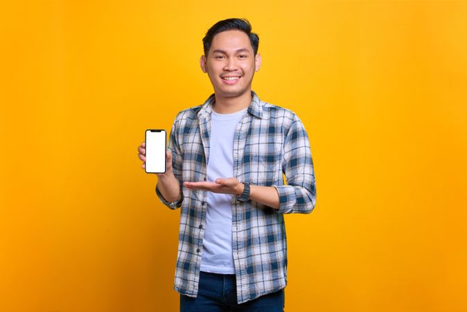 Asian male smiling and presenting smart phone with blank screen