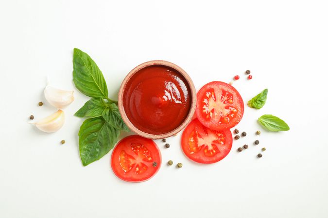 Flat lay composition with fresh cherry tomatoes slices, basil, pepper, garlic and sauce on blank background, space for text. Ripe vegetables