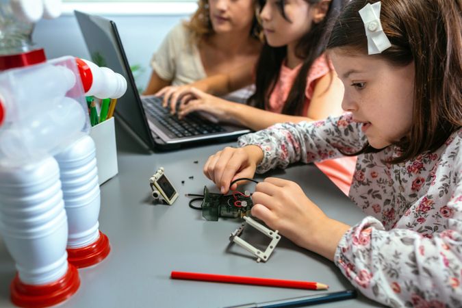 Female student connecting wire on electrical circuit in robotics class