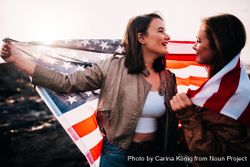 Two young women wrapping themselves themselves in the American flag P5rzP5