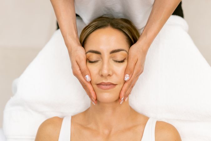 Looking down at woman having her face massaged by massage therapist