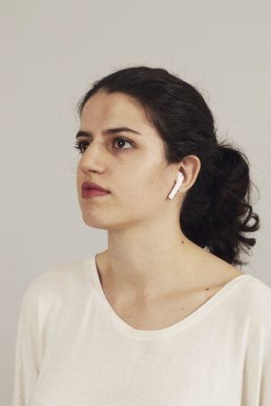 Thoughtful young female athlete listening to music in studio