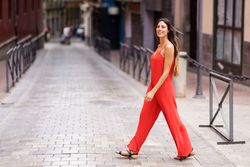 An Elegant Woman Dressed in a Striking Red Suit Walking Gracefully on an Urban Street