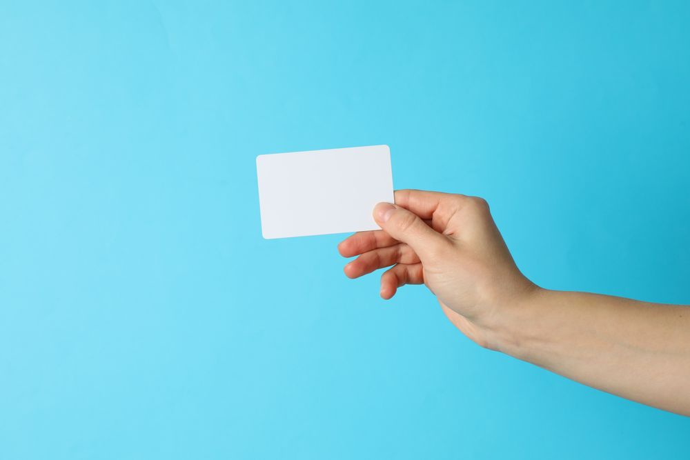 Female hand holding empty business card on blue background